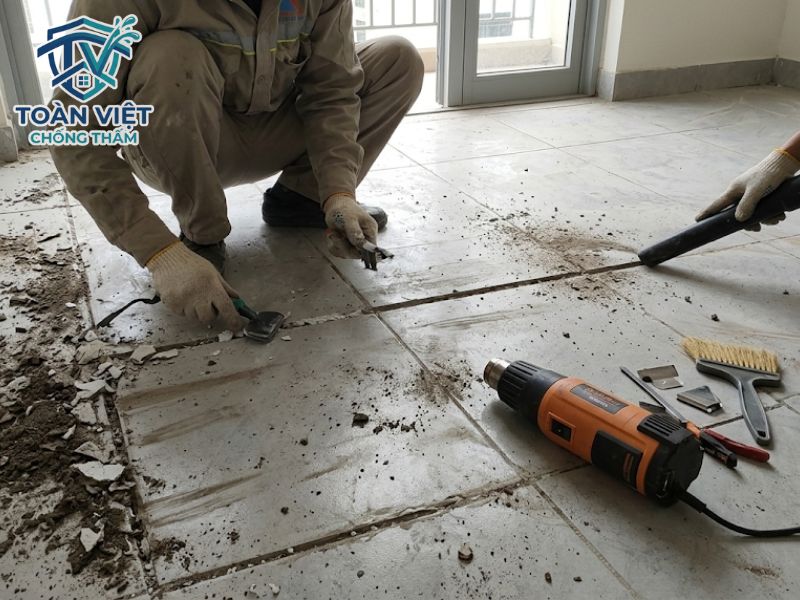 Chống thấm nhà vệ sinh không cần đục gạch có bền không? 7 Thợ kỹ thuật cạo bỏ lớp xi măng trắng cũ sâu 2-3mm và khò khô hoàn toàn bề mặt sàn trước khi thi công