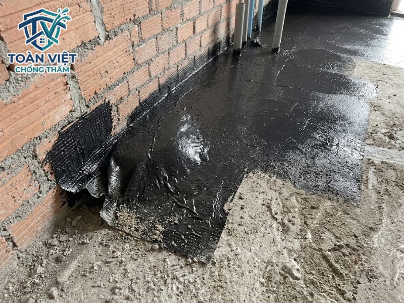 Màng PE bị phồng rộp và bong mép ở góc chân tường do mặt sàn chưa sạch bụi