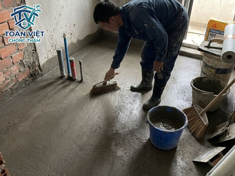 Quét lớp Sika 107 thứ nhất đều tay theo một chiều, phủ kín mặt sàn và vén cao lên chân tường 15 - 20cm